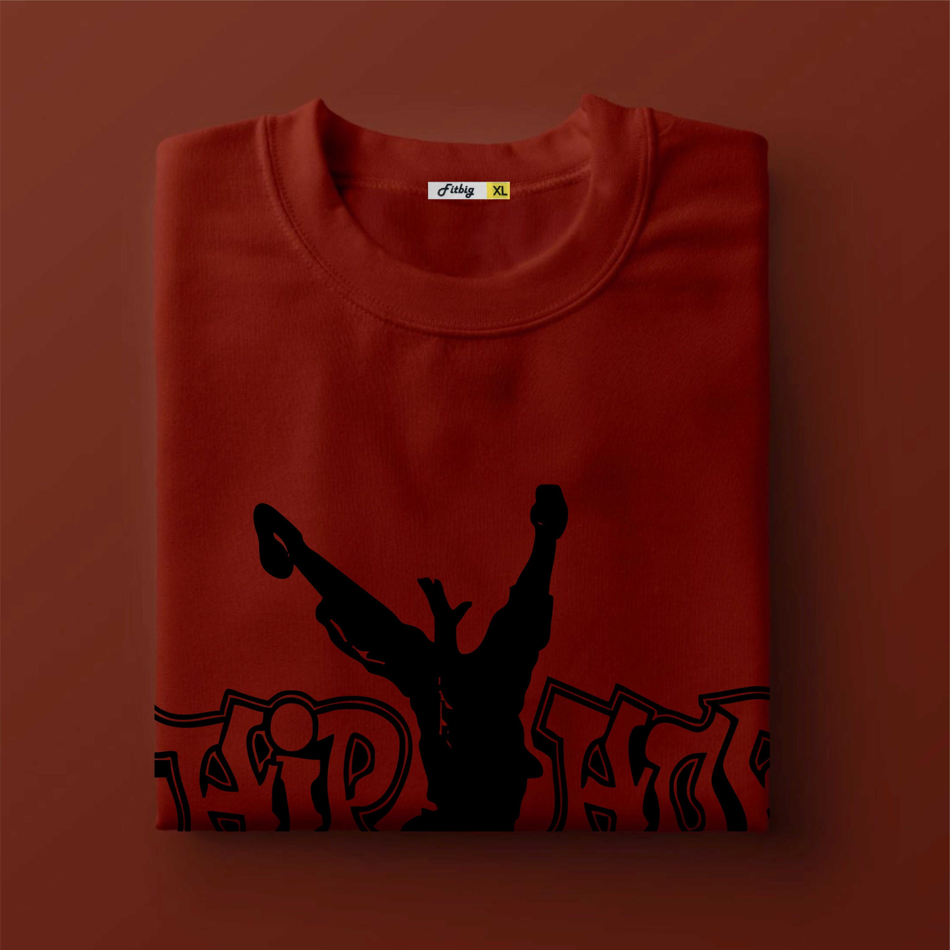 Folded red t shirt with black graphic design on a brown background