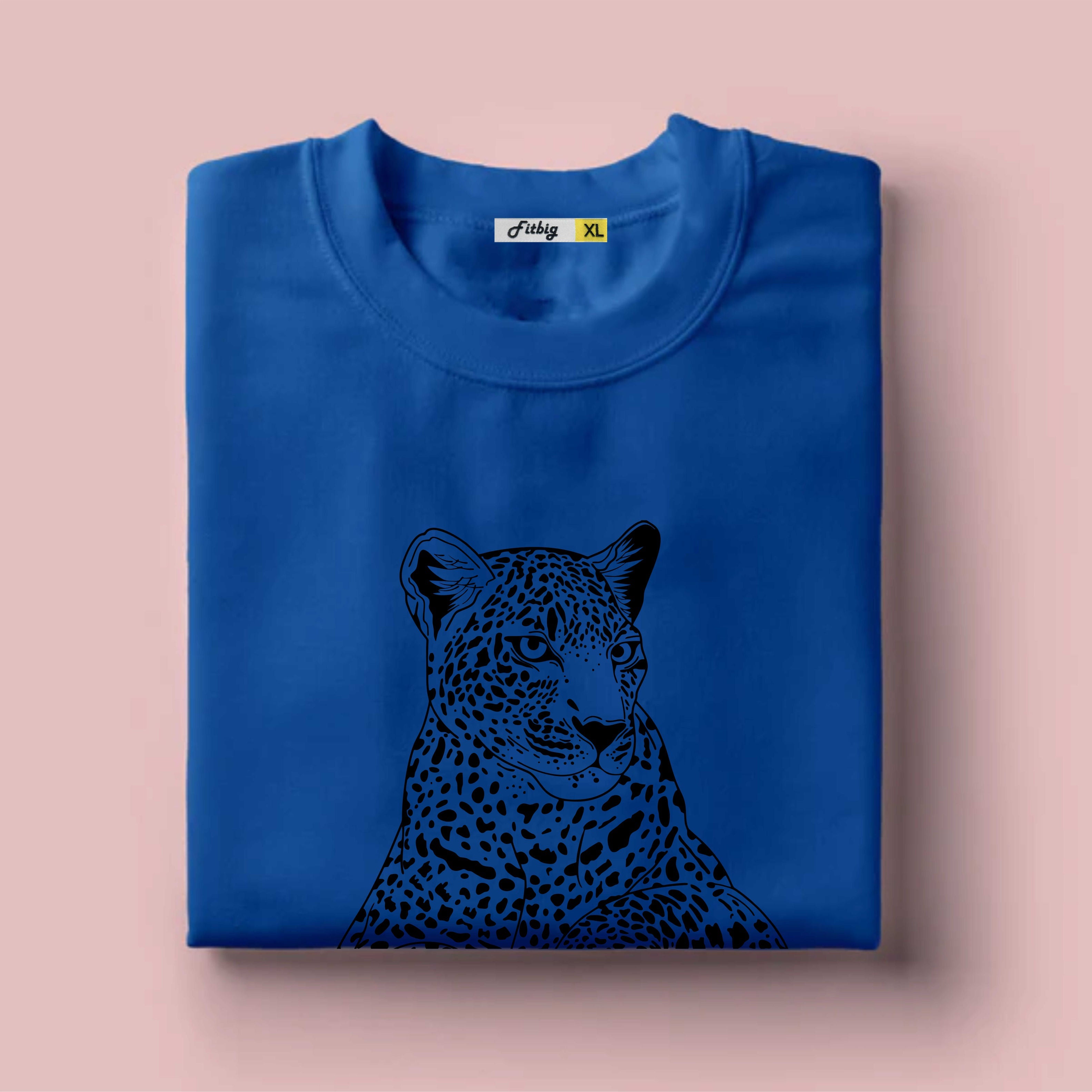 Folded blue T shirt with a black leopard design on a pink background