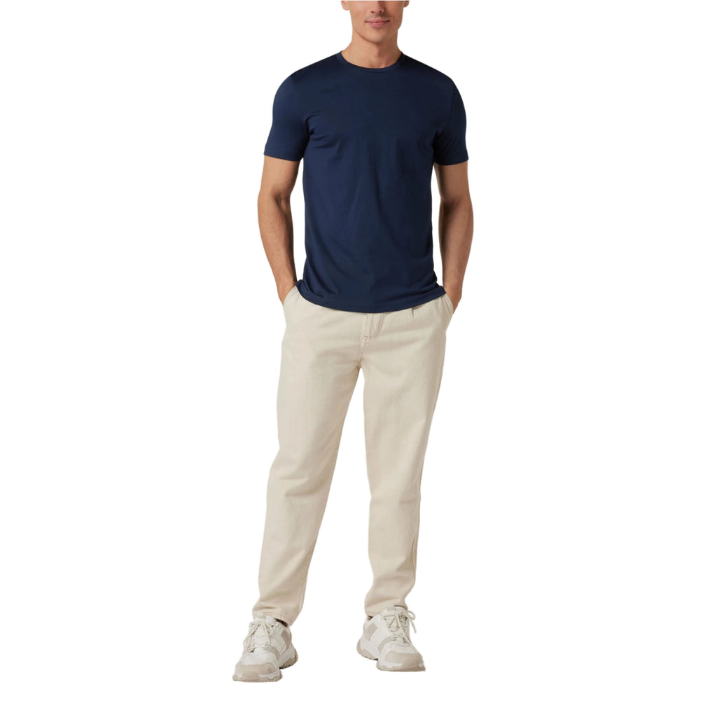 Person wearing a navy t-shirt and beige pants on a white background